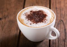 a cappuccino in a white cup on a wooden table