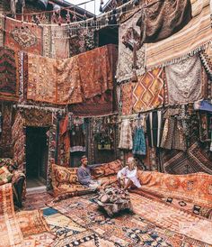 a man sitting on top of a couch surrounded by rugs