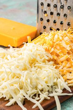 cheese and grated cheese on a cutting board next to a grater, knife and grater