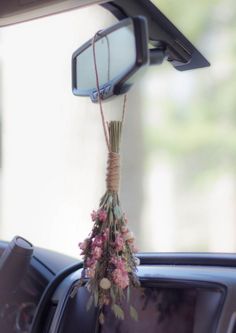 flowers tied to the dash board of a car in front of a rear view mirror