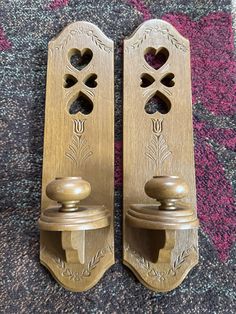 two wooden door handles on carpeted area with pink and purple rug in background, closeup