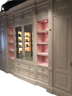 a large white cabinet with pink shelves and lights on it's doors, in front of a mirror