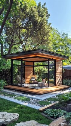 a small wooden structure in the middle of a yard with rocks and grass around it