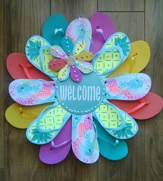 a welcome sign made out of flip flops on top of a wooden floor next to a pair of shoes