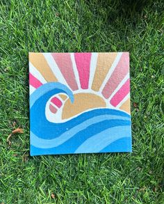 a piece of art that is sitting in the grass on some grass with it's sun and ocean waves painted on it