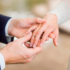 the bride and groom hold hands as they stand close to each other with their wedding rings on their fingers