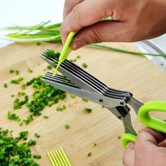 someone cutting up some green vegetables with scissors