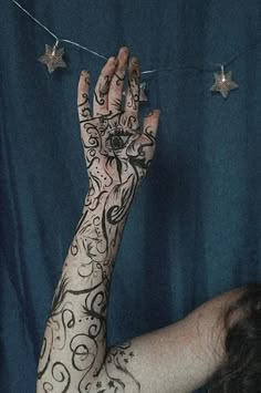 a woman with tattoos on her arm and hand reaching up to the stars above her head