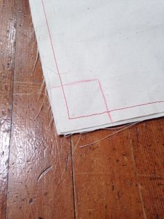 a piece of cloth that has been stitched together on a wooden floor with red thread