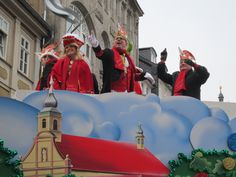 some people are standing on top of a float in a parade with buildings and trees