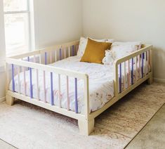 a white bed sitting next to a window in a bedroom on top of a rug