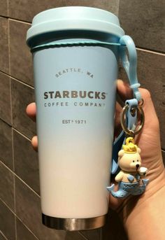 a person holding a starbucks cup with a keychain attached to it and a bear on the bottom