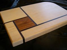 a wooden cutting board with black and brown squares on it's sides, sitting on a leather surface