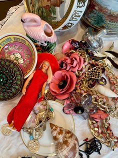 a table topped with lots of assorted jewelry and figurines on top of plates