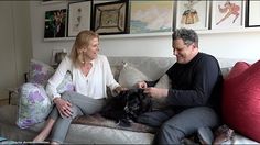 a man and woman sitting on a couch petting a dog