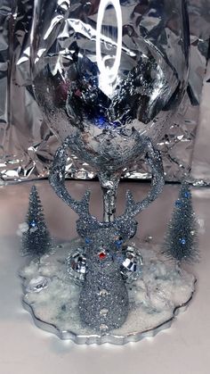 a glass bowl sitting on top of a table next to silver foil and christmas trees