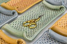 a pair of gold scissors sitting on top of a blue and yellow tray with handles