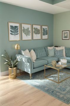 a living room with blue couches and pictures on the wall above them in gold frames