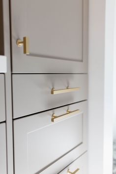 a white cabinet with brass handles and knobs