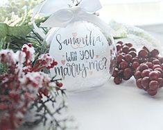 a christmas ornament sitting on top of a table next to berries and flowers