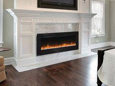 a living room with a fireplace and white furniture in the corner, along with a flat screen tv mounted on the wall