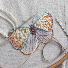 a close up of a butterfly on a piece of cloth next to scissors and thread