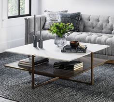 a living room with a couch, coffee table and pictures on the wall above it