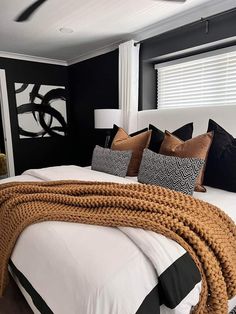 a white bed topped with lots of pillows next to a black and white bedroom wall