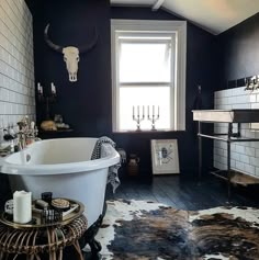 a bathroom with a tub, sink and cow skin rugs on the floor in front of a window