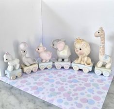 a group of small toy animals riding on top of a wooden train set with polka dot table cloth