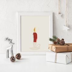 a white frame with a red candle on it next to some christmas decorations and presents