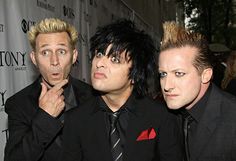 three men dressed in black and red posing for the camera with one man's hair sticking out