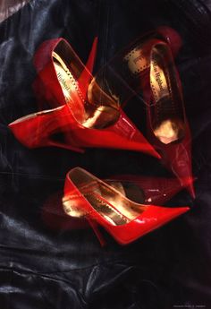 three pairs of red high heeled shoes sitting on top of a black cloth covered floor