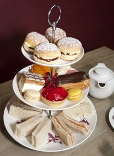 three tiered trays filled with different types of pastries and desserts on top of a wooden table