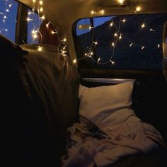 there is a bed in the back of a van with christmas lights on it's headlight