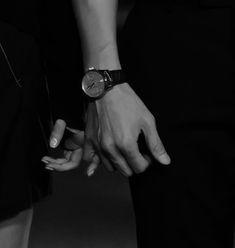 two people are holding hands in black and white, while one person is wearing a watch