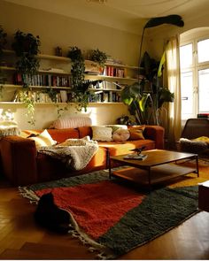 a living room filled with lots of furniture and plants on the wall above it's bookshelf