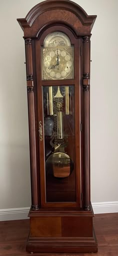 an old grandfather clock sitting on top of a hard wood floor next to a wall