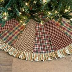 a christmas tree skirt on the floor with lights around it and plaid fabric under the tree