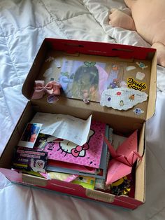 an open hello kitty box sitting on top of a bed next to a stuffed animal