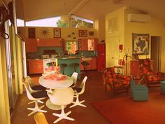 a living room filled with furniture next to an open kitchen and dining room area on top of a hard wood floor