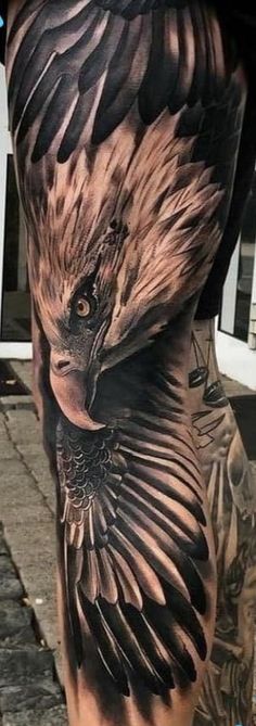 an eagle tattoo on the back of a man's leg, with black and grey ink