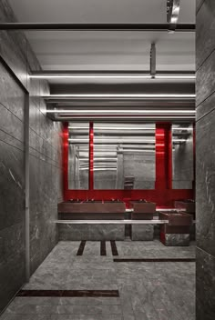 an empty room with tables and benches in the center is lit by red light from windows