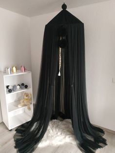 a black canopy bed in the corner of a room with white walls and flooring