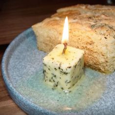 a piece of bread on a plate with a candle in the middle and some sort of food