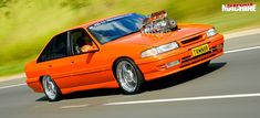 an orange car driving down the road with surfboards on it's top rack