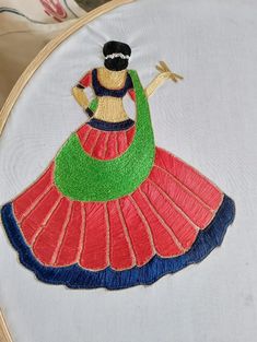 a woman in a colorful dress is embroidered onto a white cloth