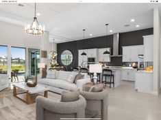 a living room filled with furniture next to a kitchen and an open concept dining area