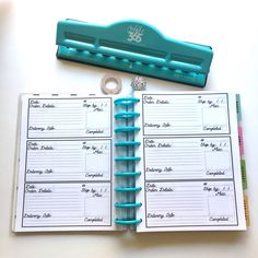 an open planner with a blue stapler on top of it next to a clipboard