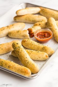 breadsticks and dipping sauce on a baking sheet